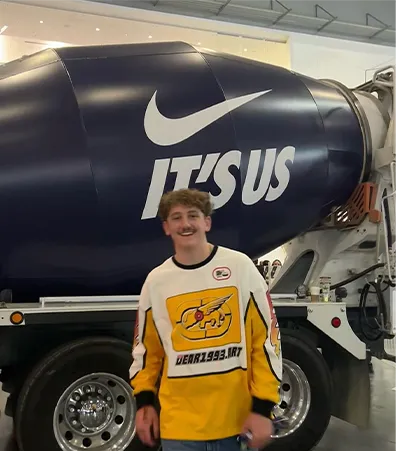 A fan in a yellow and white hockey jersey in front of the It’s Us concrete truck