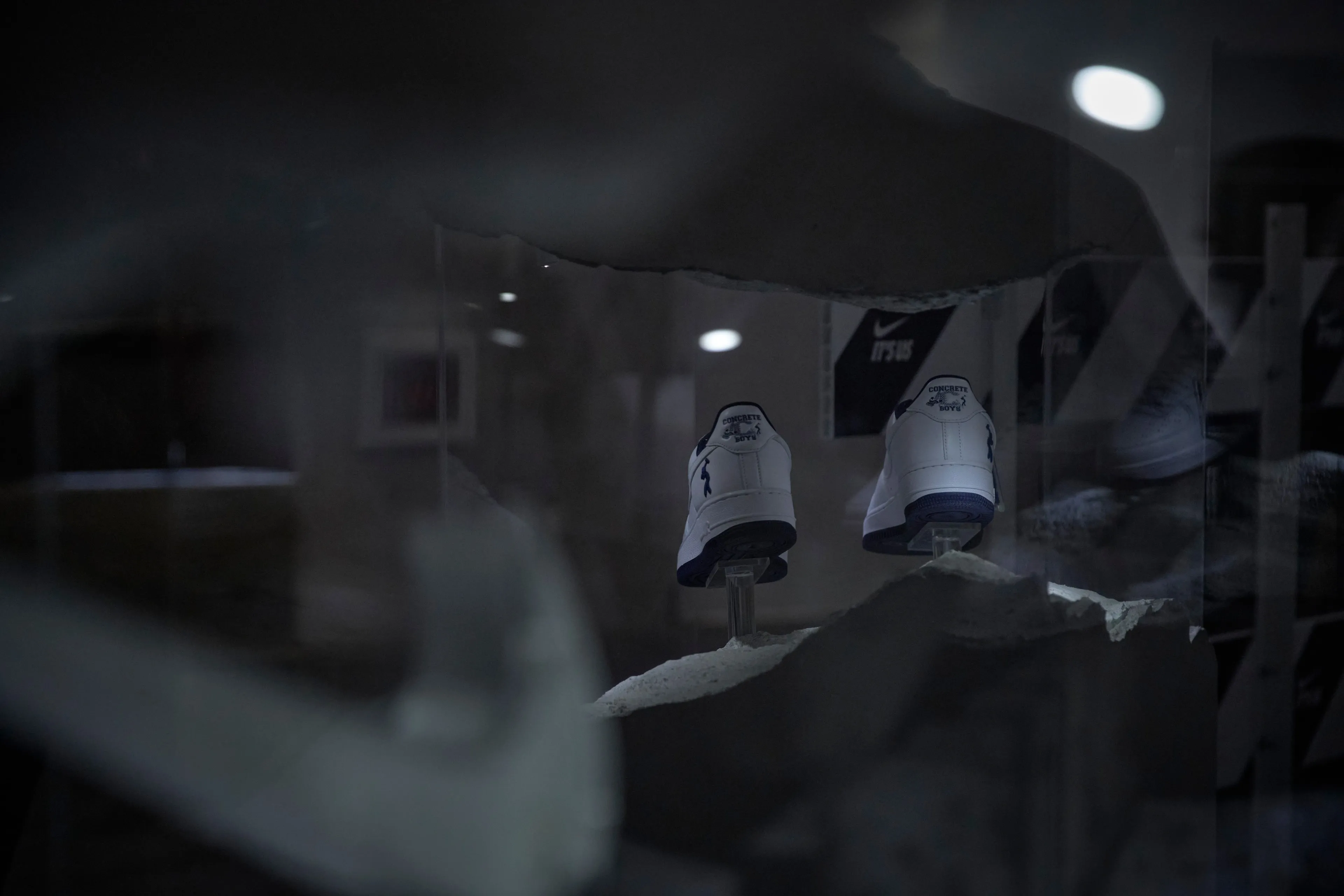Two US Force 1s on clear stands inside a smashed concrete display, the It’s Us wall behind